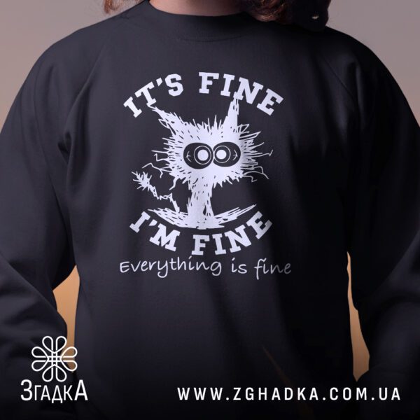 Крупний план принту "everything is fine" на чорному світшоті, що детально показує ілюстрацію.