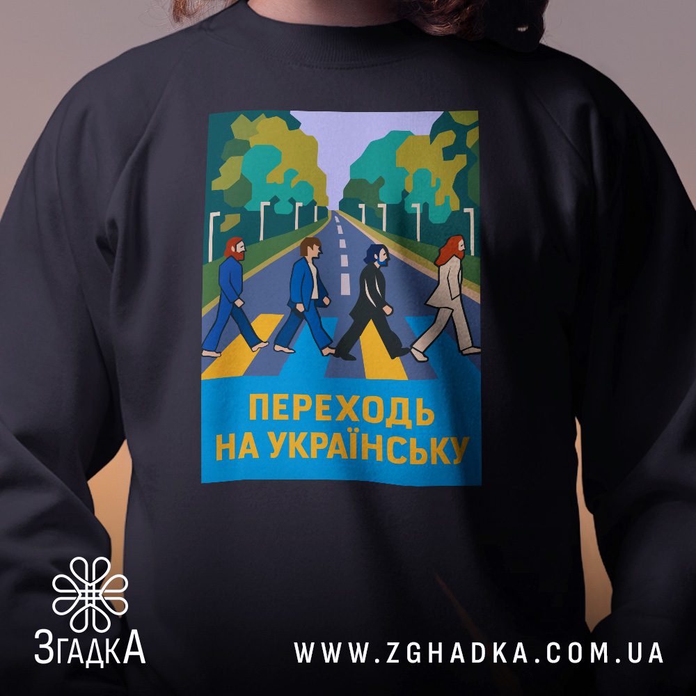 Крупний план принту "переходь на українську" на чорному світшоті, що детально показує ілюстрацію.