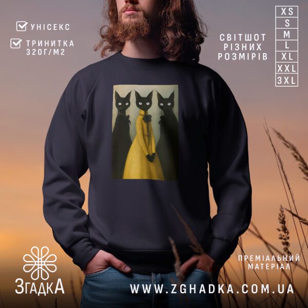 Чорний світшот з графічним принтом у центрі. На принті зображено трьох чорних котів, серед яких центральний кіт у яскравій жовтій сукні.