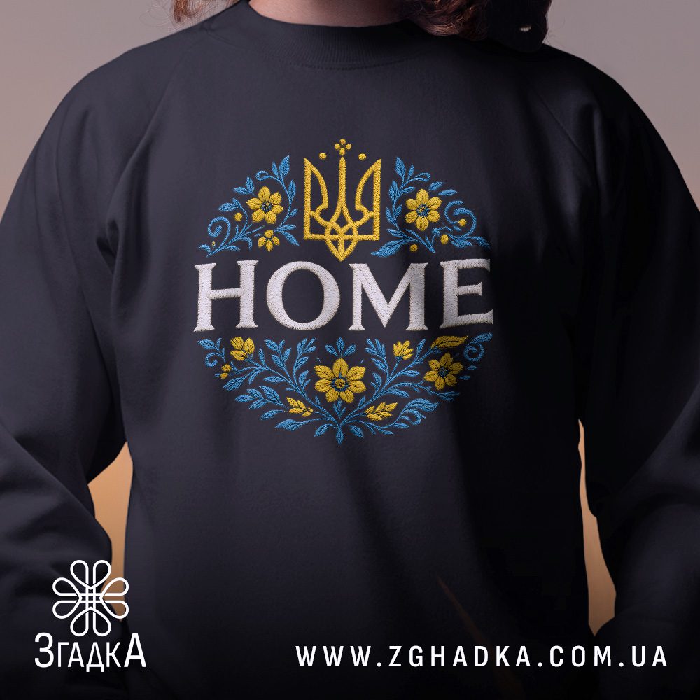 Крупний план принту "з тризубом HOME" на чорному світшоті, що детально показує ілюстрацію.