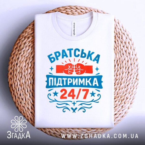 Біла футболка з принтом "Братська підтримка 24/7", складена.