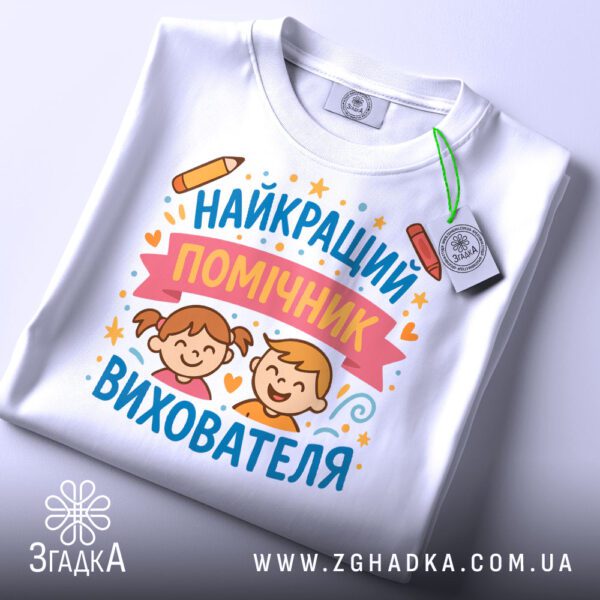 Футболка для помічника вихователя акуратно складена з біркою Згадка на білому фоні.