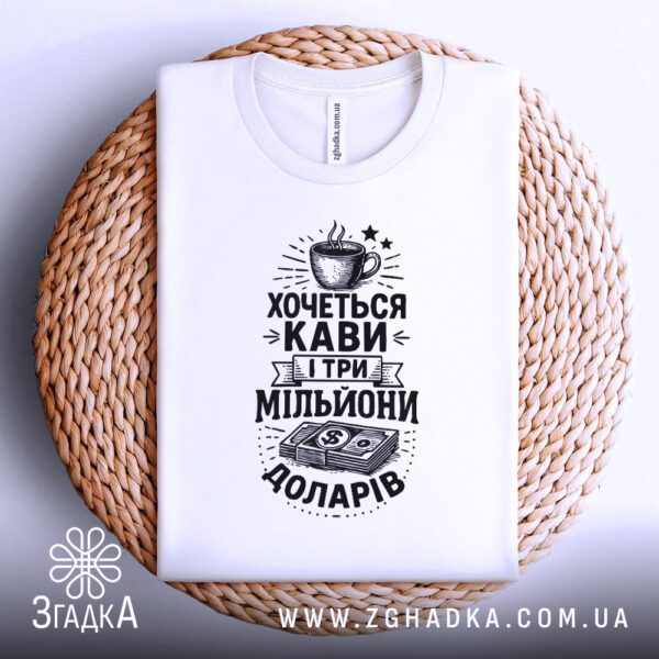 Біла футболка з принтом "Кавоман і мільйони", складена.