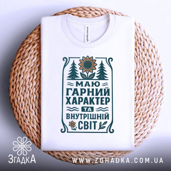 Біла футболка з принтом "Маю гарний характер та внутрішній світ", складена.