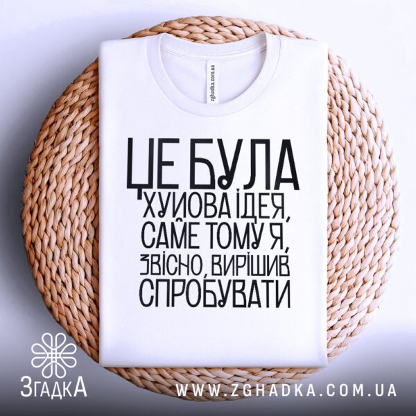 Біла футболка з принтом "Х#йова ідея гумор", складена.