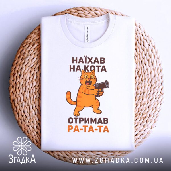 Футболка кіт з пістолетом складена на декоративній підставці.