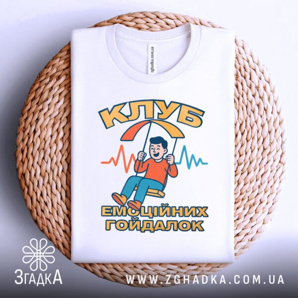 Футболка клуб емоційних гойдалок акуратно складена на плетеній підставці.