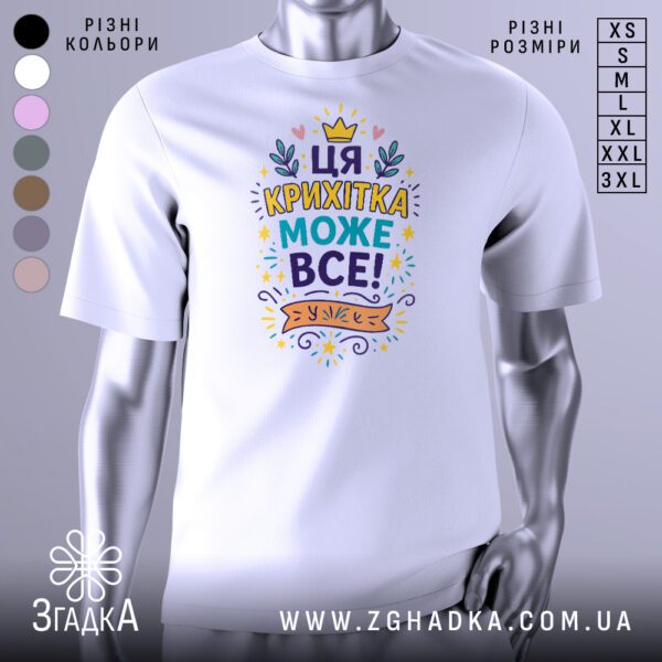Біла футболка з написом "Ця крихітка може все!" на манекені.