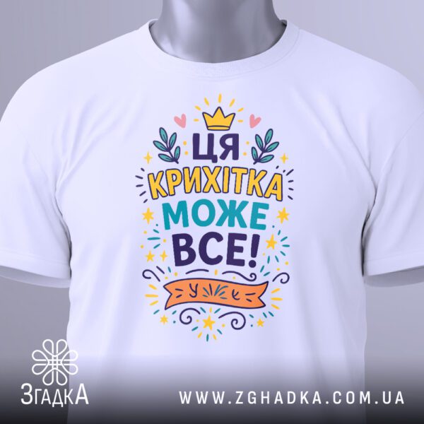 Біла футболка з написом "Ця крихітка може все!", вигляд зблизька.