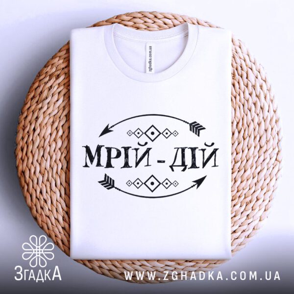 Футболка мрій дій мотив складена на круглій плетеній підкладці, вигляд зверху.