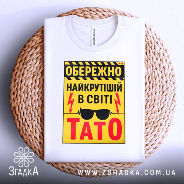 Футболка подарунок для тата складена на плетеній підставці, вигляд зверху.