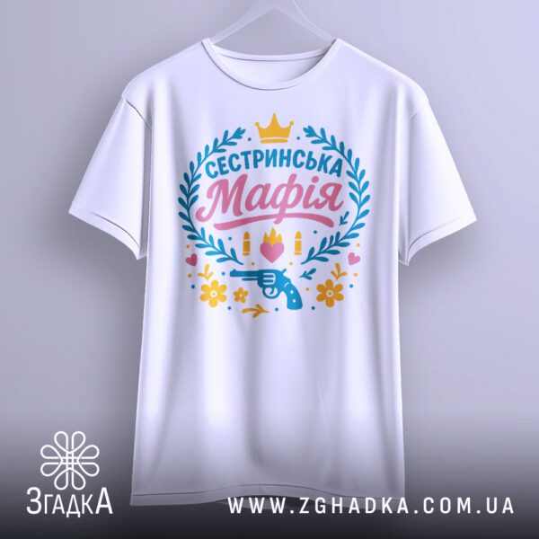 Біла футболка з принтом "Сестринська мафія", складена.