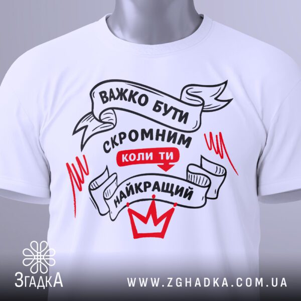 Футболка важко бути скромним білого кольору, на вішаку.