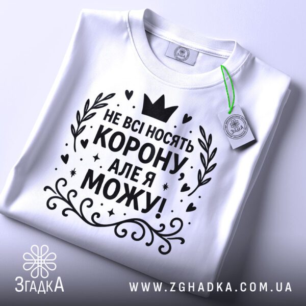 Біла жіноча футболка з принтом "Не всі носять корону", вид спереду.