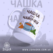 Чашка для чайочку подарункова лежить горизонтально, видно дизайн з пакетиком чаю