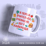 Чашка для першої вчительки, біла з яскравим принтом, видно текст на передній частині, фон світло-фіолетовий, принт містить елементи шкільної тематики, ручка стандартної форми, край рівний, глянцевий.