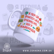 Чашка для першої вчительки, біла, з нахилом, видно текст на передній частині, фон світло-фіолетовий, принт містить шкільні символи, ручка стандартної форми, край рівний, глянцевий.