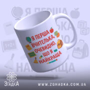 Чашка для першої вчительки, біла, з легким нахилом, текст на передній частині, фон світло-фіолетовий, принт з елементами шкільної тематики, ручка стандартної форми, край рівний, глянцевий.