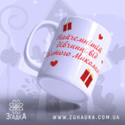 Чашка дитячий подарунок Миколай із червоним написом та малюнками сердець і подарунків.