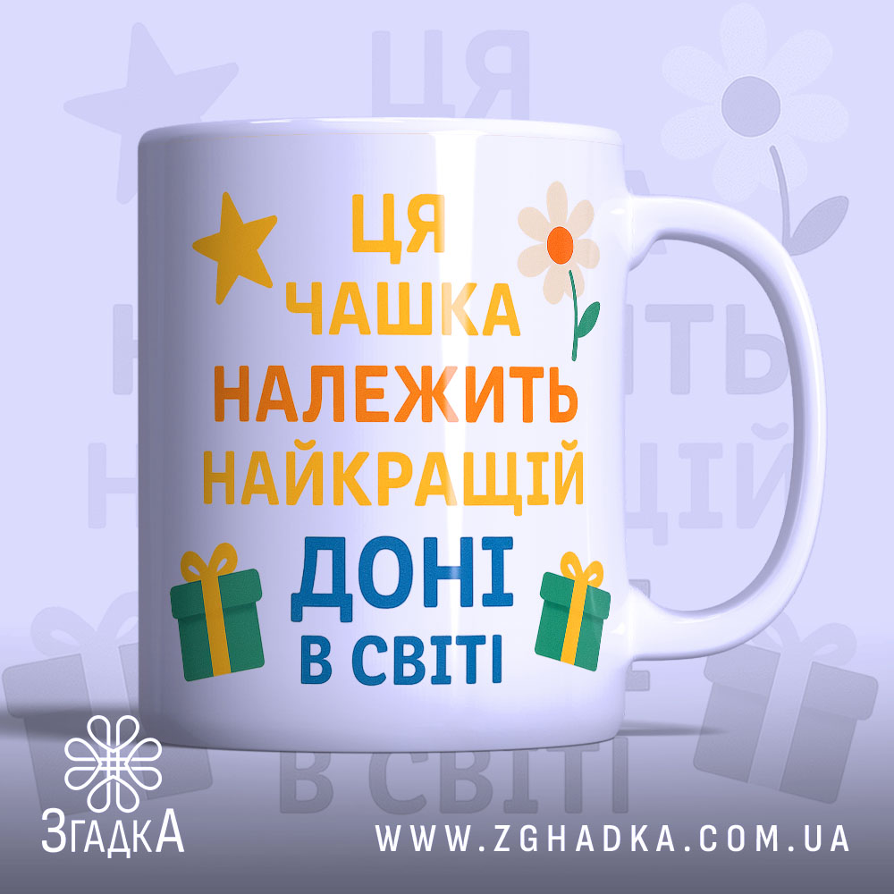 Чашка найкращій доні подарунокʼ Біла чашка з кольоровим принтом, на якому написано 'Ця чашка належить найкращій доні в світі'. Ручка чашки гладка, край рівний, фон ніжно-фіолетовий, з елементами жовтих зірочок, квітів та подарунків. Чашка має глянцеву поверхню.