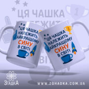 Чашка найкращому сину подарунок. Дві чашки білого кольору з однаковим принтом, розташовані під кутом. Принт містить текст синього та оранжевого кольорів, а також зображення ракети та чашки. Ручки круглі, краї рівні, поверхня глянцева. Фон світло-синій з елементами зірок.