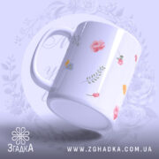 Чашка подарунок для бабусі, біла з квітковим принтом, ракурс з боку, фон світло-фіолетовий, без напису, ручка округлої форми, край гладкий, глянцевий.