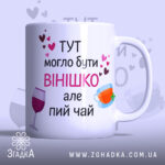 Чашка смішна для подруги, біла, з прямим ракурсом, на фоні ніжно-фіолетового кольору, з написом чорного та рожевого кольорів, з малюнками чашки та келиха, ручка класична, край гладкий, матова поверхня.