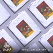 Футболка борщ українська кулінарія, біла, складена в хаотичному порядку, фон світло-сірий, принт з малюнком борщу та інгредієнтів, кольори яскраві, текст "БОРЩ" на червоному фоні.