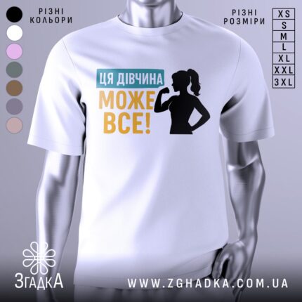 Футболка для підтримки дівчат, білого кольору, зображена на манекені, фон світло-сірий, принт містить текст "ЦЯ ДІВЧИНА МОЖЕ ВСЕ!" у жовтому та блакитному кольорах, а також силует дівчини з піднятою рукою.