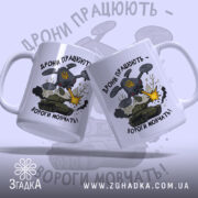 Футболка дрони працюють подарунок. Дві чашки білого кольору з глянцевою поверхнею, розташовані під кутом один до одного. Принт на обох чашках однаковий, з написом 'Дрони працюють - вороги мовчать!' та ілюстрацією дрону, що стріляє. Ручки чашок класичні, з округлою формою, краї гладкі.