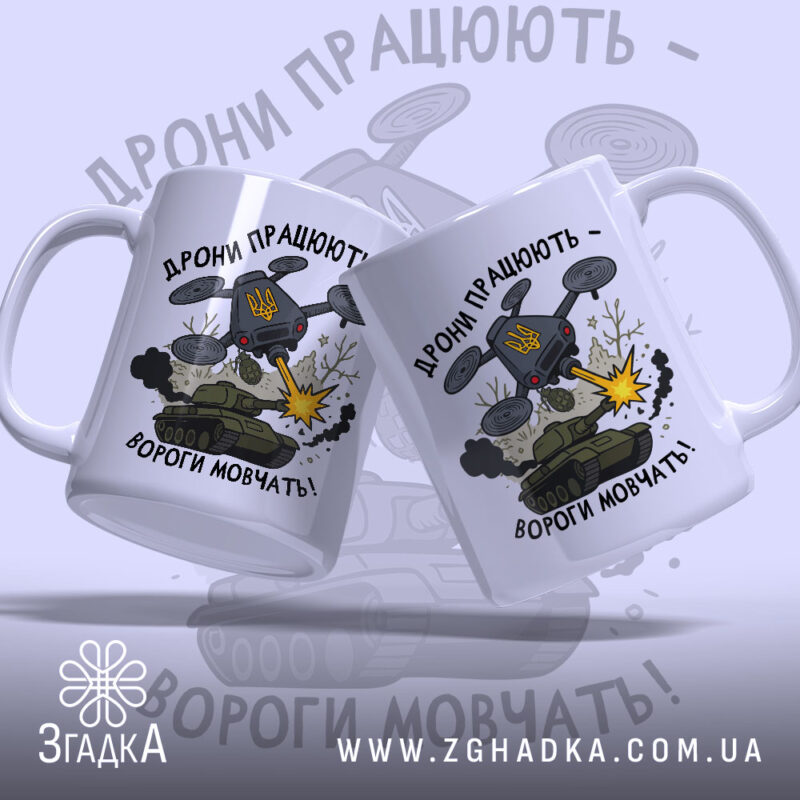 Футболка дрони працюють подарунок. Дві чашки білого кольору з глянцевою поверхнею, розташовані під кутом один до одного. Принт на обох чашках однаковий, з написом 'Дрони працюють - вороги мовчать!' та ілюстрацією дрону, що стріляє. Ручки чашок класичні, з округлою формою, краї гладкі.