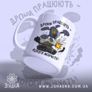 Футболка дрони працюють подарунок. Чашка білого кольору з матовою поверхнею, зображення дрону та танка на передній частині. Принт містить напис 'Дрони працюють - вороги мовчать!' та елементи графіки, такі як вибухи та дим. Ручка чашки класична, з округлою формою, край чашки гладкий.