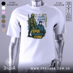 Футболка герої тримають стрій. Біла футболка з принтом, на якому зображені два чоловіки: один у військовій формі, інший у цивільному одязі. Принт виконаний у темно-зелених та жовтих тонах, на фоні видно напис 'Слава Україні'.