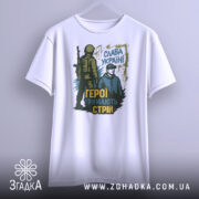 Футболка герої тримають стрій. Біла футболка, що висить на вішалці, з чітким зображенням принта. Принт містить двох чоловіків, один з яких у військовій формі, а інший у капюшоні.