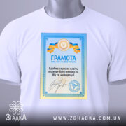 Футболка грамота з написом, білого кольору, зображена на манекені, фон світло-сірий, принт з грамотою у блакитних та жовтих кольорах, текст на українській мові.