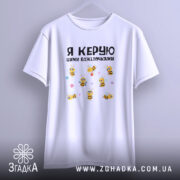 Футболка я керую бджілочками, білого кольору, підвішена на вішалці, фон світло-сірий, принт з бджілками та написом, рукави футболки вільно звисають.