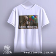 Футболка я вже старе. Біла футболка на вішалці, з принтом скелета, що тримає чашку, на фоні кольорових повітряних куль.
