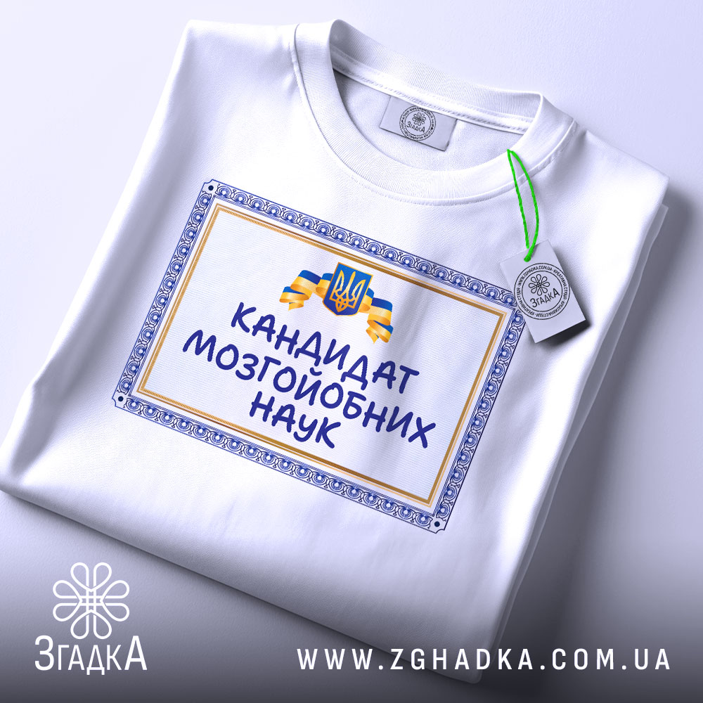 Футболка кандидат мозгойобних наук, біла, складена на столі, фон світло-сірий, принт з написом "КАНДИДАТ МОЗГЙОБНИХ НАУК" в обрамленні, з зеленим ярликом.