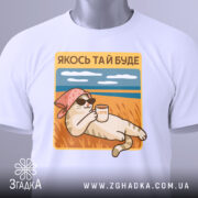 Футболка кіт якось буде. Біла футболка на манекені, ракурс спереду, фон світло-сірий. Принт з котом у рожевій бандані та сонцезахисних окулярах, що тримає чашку з написом 'LATTE', на фоні пляжу з блакитним небом і травою.