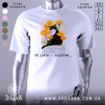 Футболка кіт не шипи, білого кольору, зображена на манекені, фон світло-сірий, принт з чорним котом на фоні жовтих і рожевих квітів, текст під принтом чорний.