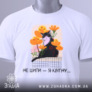 Футболка кіт не шипи, білого кольору, зображена на манекені, фон світло-сірий, принт з чорним котом серед жовтих і рожевих квітів, текст під принтом чорний.