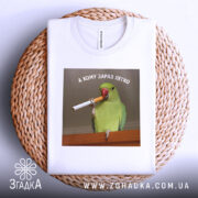 Футболка кому зараз легко, біла, зображена на круглому кошику, фон світлий, принт з папугою, що тримає сигарету, текст зверху: 'А КОМУ ЗАРАЗ ЛЕГКО'.