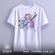 Футболка краса рятує світ. Біла футболка, підвішена на вішалці, з принтом, що зображає персонажа з короною і битою. Фон світлий, принт кольоровий.