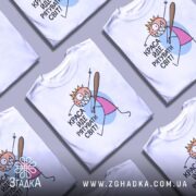 Футболка краса рятує світ. Білі футболки, складені в хаотичному порядку, з принтом, що зображає персонажа з короною і битою. Фон світлий, футболки розташовані близько одна до одної.