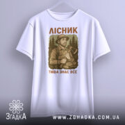 Футболка лісник тиша знає, біла футболка на вішалці, ракурс спереду, фон світлий, принт з лісником та текстом.