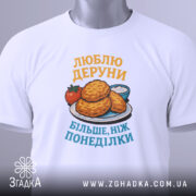 Футболка люблю деруни подарунок, біла, зображена на манекені, фон світло-сірий, принт з картинкою дерунів на тарілці з помідором і соусом, текст жовтим і блакитним кольором.