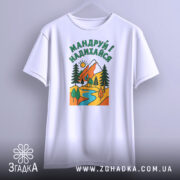 Футболка мандруй і надихайся, біла, з фронтального ракурсу, на вішалці, фон світло-сірий, принт з гірським пейзажем, річкою та деревами, кольори яскраві: червоний, зелений, жовтий, блакитний.