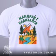 Футболка мандруй і надихайся, біла, з фронтального ракурсу, на манекені, фон світло-сірий, принт з гірським пейзажем, річкою та деревами, кольори яскраві: червоний, зелений, жовтий, блакитний.