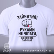 Футболка моя вас зафігачить. Біла футболка з коротким рукавом, показана з фронтального ракурсу на фоні світло-сірого градієнту. Принт з зображенням кулака з червоною перснею та текстом, що говорить про зайнятість.