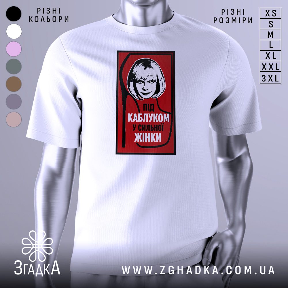 Футболка напис під каблуком, біла, зображена на манекені, фон світло-сірий, принт червоний з чорною обводкою, на якому зображена жінка з коротким волоссям та написом 'ПІД КАБЛУКОМ У СИЛЬНОЇ ЖІНКИ'.